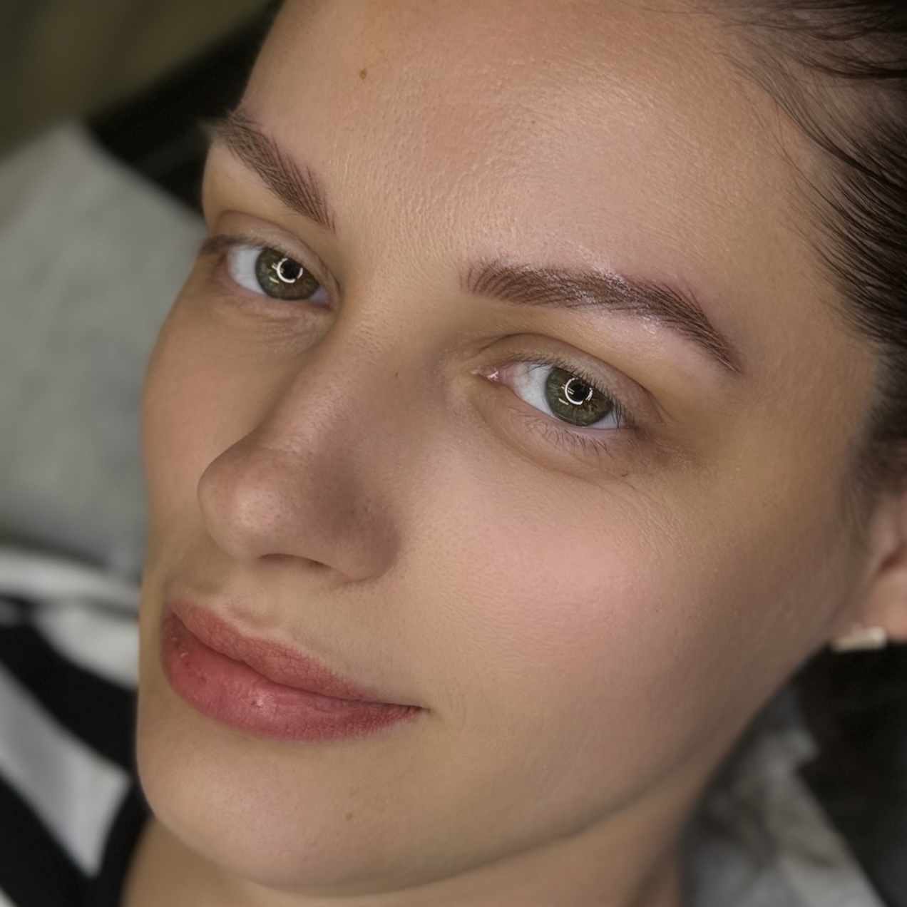 woman who has received permanent makeup on two facial areas: hairstroke nano brows and lip blush. The image highlights the natural and refined look of the hairstroke brows and the subtle, flattering color enhancement of the lip blush.